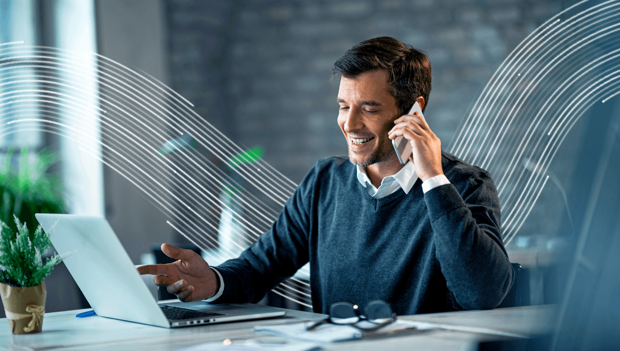 Smiling man talking on the phone and using his computer